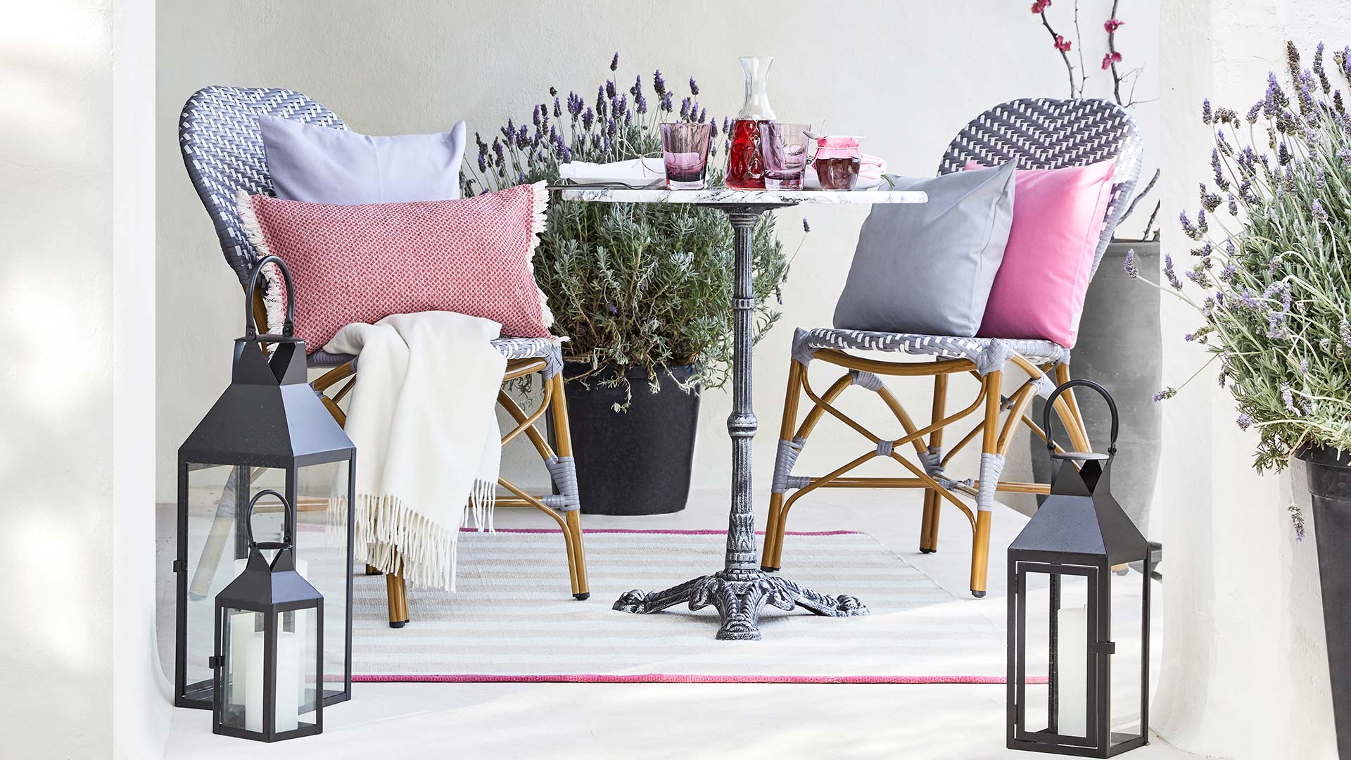 French Bistro 浅灰色背景有灰色和枚红色抱枕装饰的藤编织椅子阳台家具